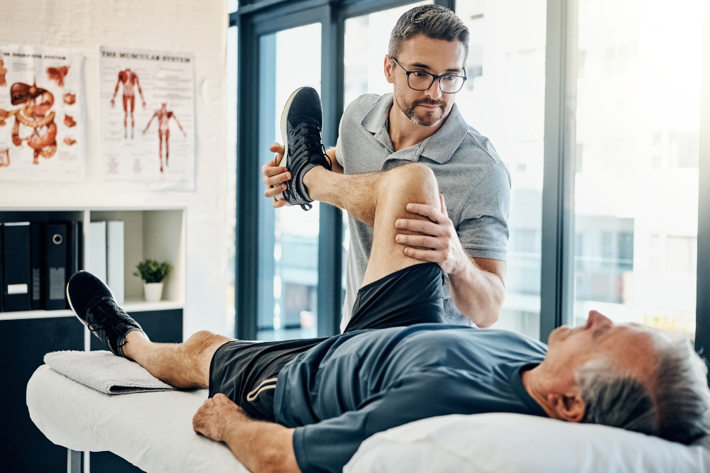 A physiotherapist stretching a patient's leg during a rehabilitation session.
